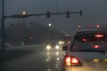 Cars driving at rainy night at traffic lights on american wide road intersection in city area. Transportation system in Royalty Free Stock Photo