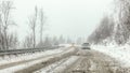 Cars driving on snow covered forest road during snowstorm, fog in disance, view from car behind. Dangerous driving conditions Royalty Free Stock Photo