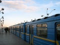 Cars of an electric subway train at a ground station in perspective. Unidentified passengers are walking in the distance Royalty Free Stock Photo