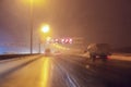 Cars fast drive on the winter speedway or highway with roadway lighting in a snow storm in the twilight when snow with