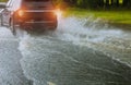 Spraying water of a car moving driving car on flooded road during flood caused by torrential rains. Cars float on water, flooding