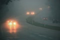 Cars in the fog. Bad winter weather and dangerous automobile traffic on the road. Light vehicles in fog. Royalty Free Stock Photo