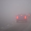 Cars in the fog. Bad winter weather and dangerous automobile traffic on the road. Light vehicles in fog. Royalty Free Stock Photo