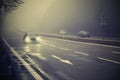 Cars in the fog. Bad winter weather and dangerous automobile traffic on the road. Light vehicles in foggy day Royalty Free Stock Photo