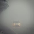 Cars in the fog. Bad winter weather and dangerous automobile traffic on the road. Light vehicles in foggy day Royalty Free Stock Photo