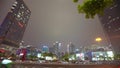 Cars go on the background of tall buildings at night. Guazhou, cars driving on the road, skyscrapers in the background