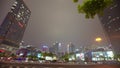 Cars go on the background of tall buildings at night. Guazhou, cars driving on the road, skyscrapers in the background