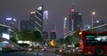 Cars go on the background of tall buildings at night. Guazhou, cars driving on the road, skyscrapers in the background