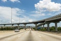Cars in a highway in the outskirts of the city of Houston with a overpass and stack intercharges