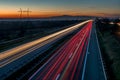 Highway at sunset, vehicles driving in two directions leaving trails of light