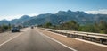 Cars motor down highway through coastal foothills and mountains of Spain. Royalty Free Stock Photo