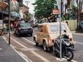 Cars and a motorcycle parked alongside the sidewalk in Denpasar city Indonesia during the daytime