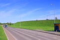 Cars move on asphalt road near hill in green grass