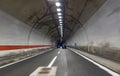 Cars move in a tunnel through a mountain on a freeway.