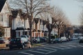 Cars parked in front of a row of Edwardian houses on a street in Palmers Green, London, UK