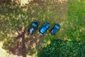 Cars parked on the lawn in the middle of the trees and on the grass. Flat aerial view