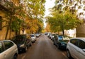 cars parked on a tree lined street outside a home in fall