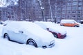 Cars on parking covered snow in snowbank after snowfall and blizzard in winter