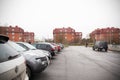 Cars in parking lot and red brick houses, city street - Saint Petersburg, Russia, November 2021