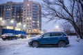 Cars in a parking lot in winter near a residential building in the snowfall