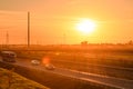 Cars passing by the highway, orange sunset over the highway