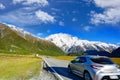 Cars run on highways in the morning with blue skies and clouds in summer. There are green grass