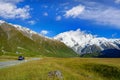 Cars run on highways in the morning with blue skies and clouds in summer. There are green grass beside the roads