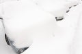 Cars are standing behind each other covered with snow.