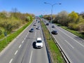 Cars on the straight highway with green stripe and street lamps in between the two main lines Royalty Free Stock Photo