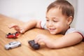 Cars, toys and boy kid by table playing for learning, development and fun at modern home. Cute, sweet and young child Royalty Free Stock Photo