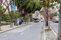 cars, trucks and buses driving along a street with lush green trees and autumn colored trees, apartments and retail stores