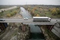 Cars and trucks pass over an old and rusty metallic bridge