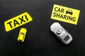 Carsharing vs taxi concept. Comparing carsharing system and taxi. Toy cars and text signs on black background top view