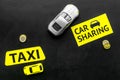 Carsharing vs taxi concept. Comparing carsharing system and taxi. Ship trip concept. Toy cars ans coins on black