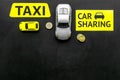 Carsharing vs taxi concept. Comparing carsharing system and taxi. Ship trip concept. Toy cars ans coins on black