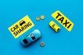 Carsharing vs taxi concept. Comparing carsharing system and taxi. Ship trip concept. Toy cars ans coins on blue