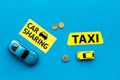 Carsharing vs taxi concept. Comparing carsharing system and taxi. Ship trip concept. Toy cars ans coins on blue