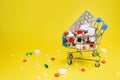 cart full of pills and vitamins on bright yellow background.