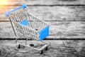 Cart from the grocery store on the old wooden background. Empty shopping trolley. Royalty Free Stock Photo