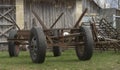 A horse-drawn cart on car wheels standing in front of a wooden barn.