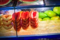 Cart of street fruit vendor with sliced papaya, melon, watermelon and mango on tray for sale on the street in Bangkok night mark