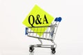 Cart and the text Q and A means questions and answers on yellow paper, business concept, over white background. Copy space Royalty Free Stock Photo