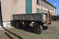 The cart from the tractor is parked near the brick buildings