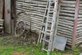 A cart wheel, a wooden ladder against the wall of an old log village house Royalty Free Stock Photo