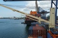 Container ship equipped with ship cranes during cargo operation loading and discharging by gantry cranes.