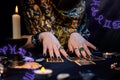 Cartomancy. A fortune teller reads Tarot cards. On the table are candles. Hands close up. Zodiac circles are located in