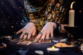 Cartomancy. A fortune teller reads Tarot cards. On the table are candles and fortune-telling objects and sparks. Hands close up. Royalty Free Stock Photo