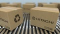 Carton boxes with HITACHI logo move on roller conveyor. Realistic 3D rendering