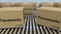 Carton boxes with PANASONIC logo move on roller conveyor. Realistic 3D rendering