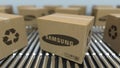 Carton boxes with SAMSUNG logo move on roller conveyor. Realistic 3D rendering